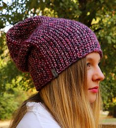 a woman with long hair wearing a purple knitted hat and looking off into the distance