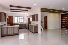 an empty kitchen and living room in a house with white floors, brown cabinets and wood trimmings