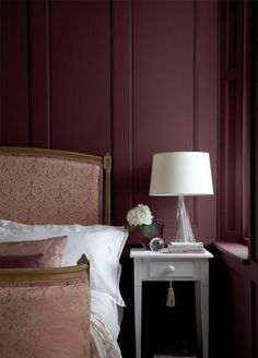 a bedroom with purple walls and a white nightstand next to the bed in front of it