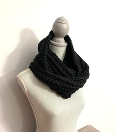 a white mannequin wearing a black knitted scarf on top of a dummy