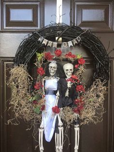 a couple dressed up as skeletons in front of a door with flowers and skeleton decorations