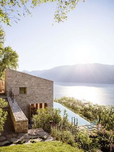 an outdoor swimming pool next to a stone building with a view of the water and mountains