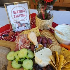 a platter with crackers, cucumbers, grapes, cheese and fruit