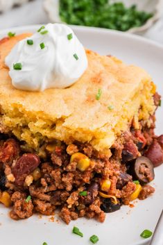 a piece of cornbread casserole on a plate with sour cream on top