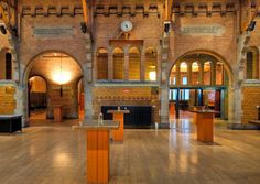 the inside of an old brick building with wooden floors and arches on either side of it