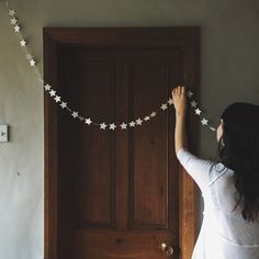 a woman is hanging star garland on the door