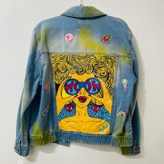 a jean jacket with an image of a woman's face painted on the back