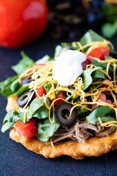 a pizza topped with lettuce, olives, tomatoes and other toppings