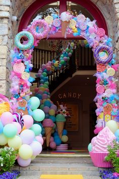 an entrance to a candy shop decorated in pastel colors with balloons and candies