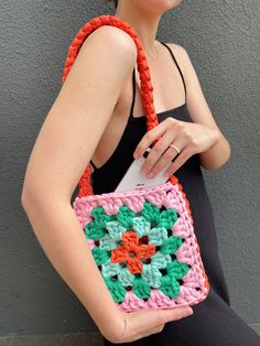 a woman is holding a crocheted purse