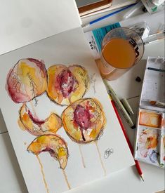 an artist's work with watercolors and paintbrushes on the table