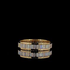 two gold rings with baguettes and diamonds on them, against a black background