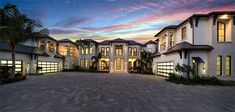 a large white house with lots of windows and palm trees on the side of it