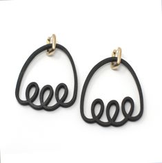 two pairs of black and gold earrings on a white surface with the word love written in it