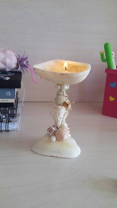 there is a candle that is on top of a small stand with shells and seashells