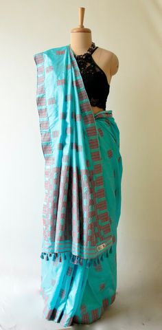 Genuine Handloom light blue Assam Silk Sari / Mulberry Silk Saree form our looms in Assam . Mulberry Silk is known as ' Pat silk ' in the region.  The Sari has Mulberry Silk in the warp and Mulberry Silk in the weft and the interwoven motifs are in cotton.  The Sari's motifs are typical tribal motifs of the region .  It is ideal for any formal occasion .  It comes with a plain blue blouse piece with the borders as in the saree .  The blouse in the images is for photography purposes only .  Lengt Blue Bohemian Traditional Wear With Patterns, Bohemian Blue Saree With Traditional Patterns, Blue Cotton Traditional Wear With Motifs, Blue Traditional Wear With Traditional Patterns In Cotton, Blue Art Silk Saree For Festivals, Blue Cotton Traditional Wear With Traditional Patterns, Blue Cotton Traditional Wear With Traditional Drape, Blue Cotton Saree With Traditional Patterns, Blue Saree With Weaving Work For Festivals