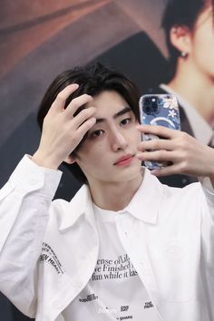 a young man is holding his cell phone up to his face and looking at the camera