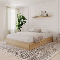 a bed sitting on top of a wooden floor next to a plant in a bedroom