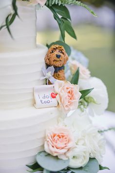 a close up of a white cake with flowers and a dog figurine on top