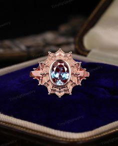 a ring with an oval blue stone in it sitting on top of a velvet case