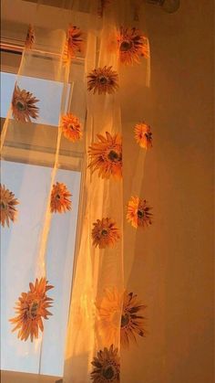 the sunflowers are hanging from the sheer curtain in the window, and they look like they're coming out of the sky