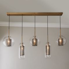 four lights hanging from a wooden beam with clear glass globes on the bottom and sides