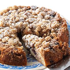 a blue and white plate topped with a cake covered in crumbled toppings