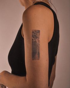 a woman with a lightning tattoo on her left arm and right arm behind her back