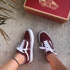 a person's feet wearing red and white vans with the box in front of them