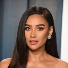 a woman with long dark hair and earrings on her head is looking at the camera