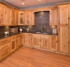 a large kitchen with wooden cabinets and black counter tops, along with wood flooring