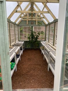 the inside of a small greenhouse with benches and plants in it's center area