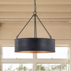 a chandelier hanging from the ceiling in a room with large windows and wooden floors