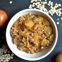 a bowl filled with oatmeal next to apples