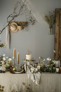 a table with candles, flowers and other items on it in front of a wall