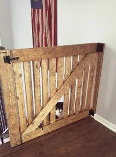 the cat is hiding in the wooden gate on the floor next to the american flag