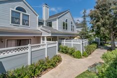 an apartment complex with white picket fence and trees