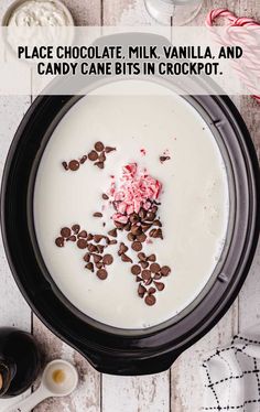 a bowl filled with milk and chocolate chips on top of a white wooden table next to candy