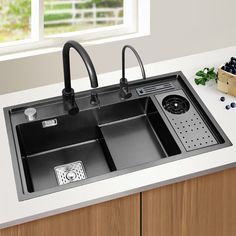 a kitchen sink sitting on top of a counter next to a box of blueberries