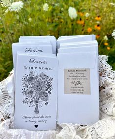 two cards are sitting on top of a doily in front of some wildflowers