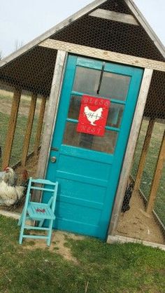 a blue door and chair in front of a chicken coop with chickens on the grass