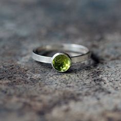 A beautiful, rose-cut Peridot gem sparkles in a sterling silver bezel, set on a flat sterling silver band. The Peridot gem is expertly faceted in a gorgeous rose cut and measures 6mm in diameter. A rose-cut gem has a flat base and a crown made up of triangular facets that are symmetrically arranged and rise to form a point at the top of the stone. The sterling silver band is 2mm high and 1mm thick. If you are at all unsure of the ring size, please purchase this easy, reusable finger sizer before Peridot Gemstone Stackable Rings As Gift, Peridot Gemstones Birthstone For Anniversary, Peridot Birthstone Gemstones For Anniversary, Modern Peridot Jewelry As A Gift, Modern Peridot Jewelry For Gift, Stackable Peridot Jewelry As Gift, Stackable Peridot Jewelry Gift, Peridot Bezel Setting Promise Ring, Peridot Promise Ring With Bezel Setting