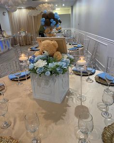 a teddy bear sitting on top of a white bag filled with flowers and blue hydrangeas