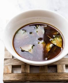 a white bowl filled with soup on top of a wooden tray