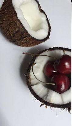 two pieces of coconut with cherries in them on a white plate next to another piece of fruit