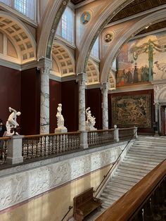 the inside of a building with statues and paintings on the walls, along with stairs