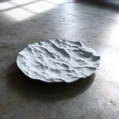 a white plate sitting on top of a floor next to a window in a room