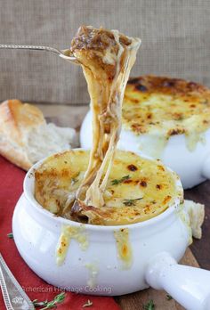 a piece of cheese being lifted out of a casserole dish with bread in the background