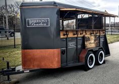 an old fashioned food truck is parked on the side of the road in front of a fence