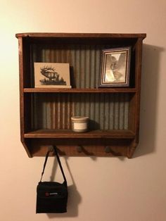 a wooden shelf with some pictures on it and a purse hanging from the wall next to it